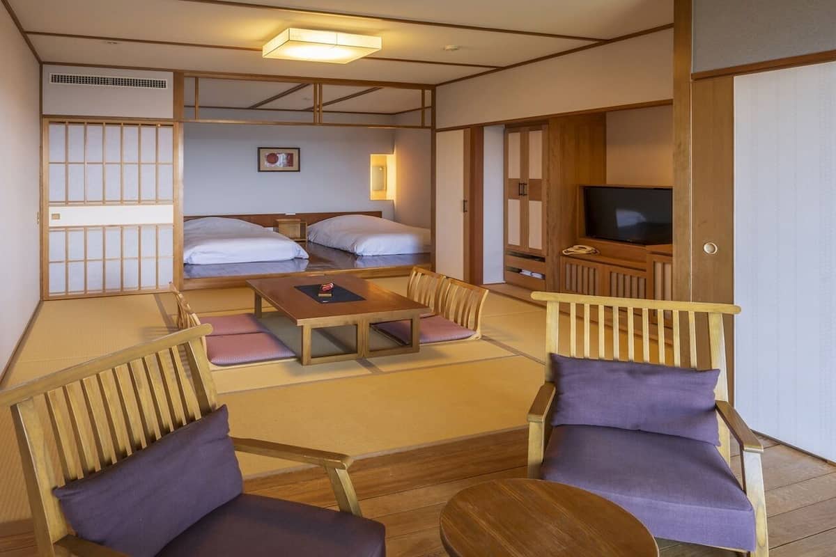 Perinteinen japanilaistyylinen huone, jossa on tatamimatto lattiana, matala pöytä, kaksi tatamialustaa, televisio ja liukuovi.