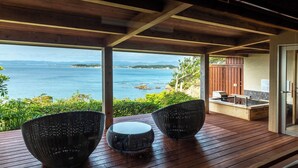 A wooden deck with two woven chairs and a small table, overlooking a body of water with distant land. - Hamadachidori no Yu Kaishu (Shirahama)