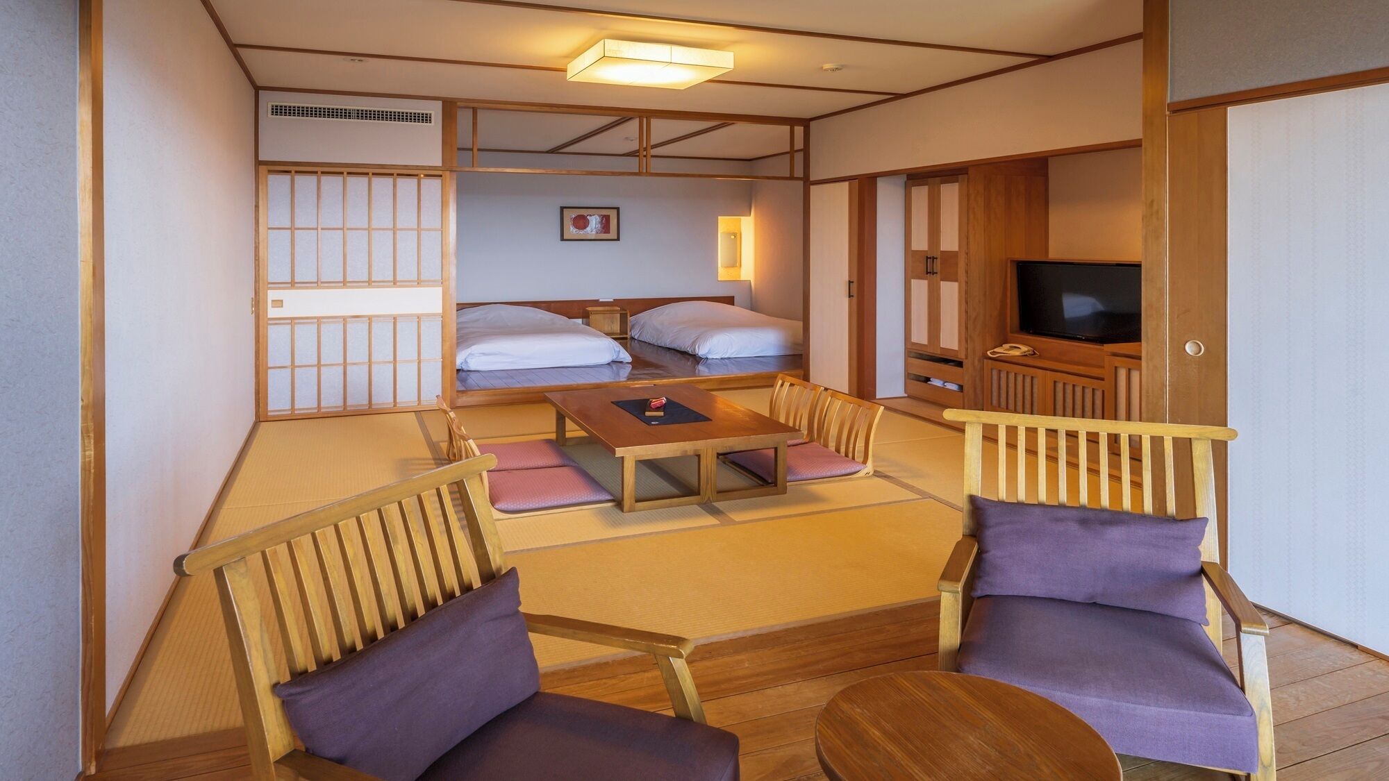 Ein traditioneller japanischer Raum mit Tatami-Bodenbelag, einem niedrigen Tisch und Holzmöbeln.