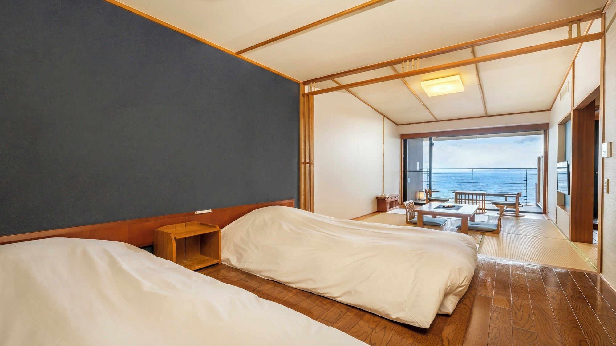 Ein Zimmer mit zwei Betten, einem kleinen Nachttisch und einem Balkon mit Meerblick.