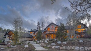 A large, multi-story lodge with a stone facade, multiple balconies, and a stone pathway leading to the entrance.