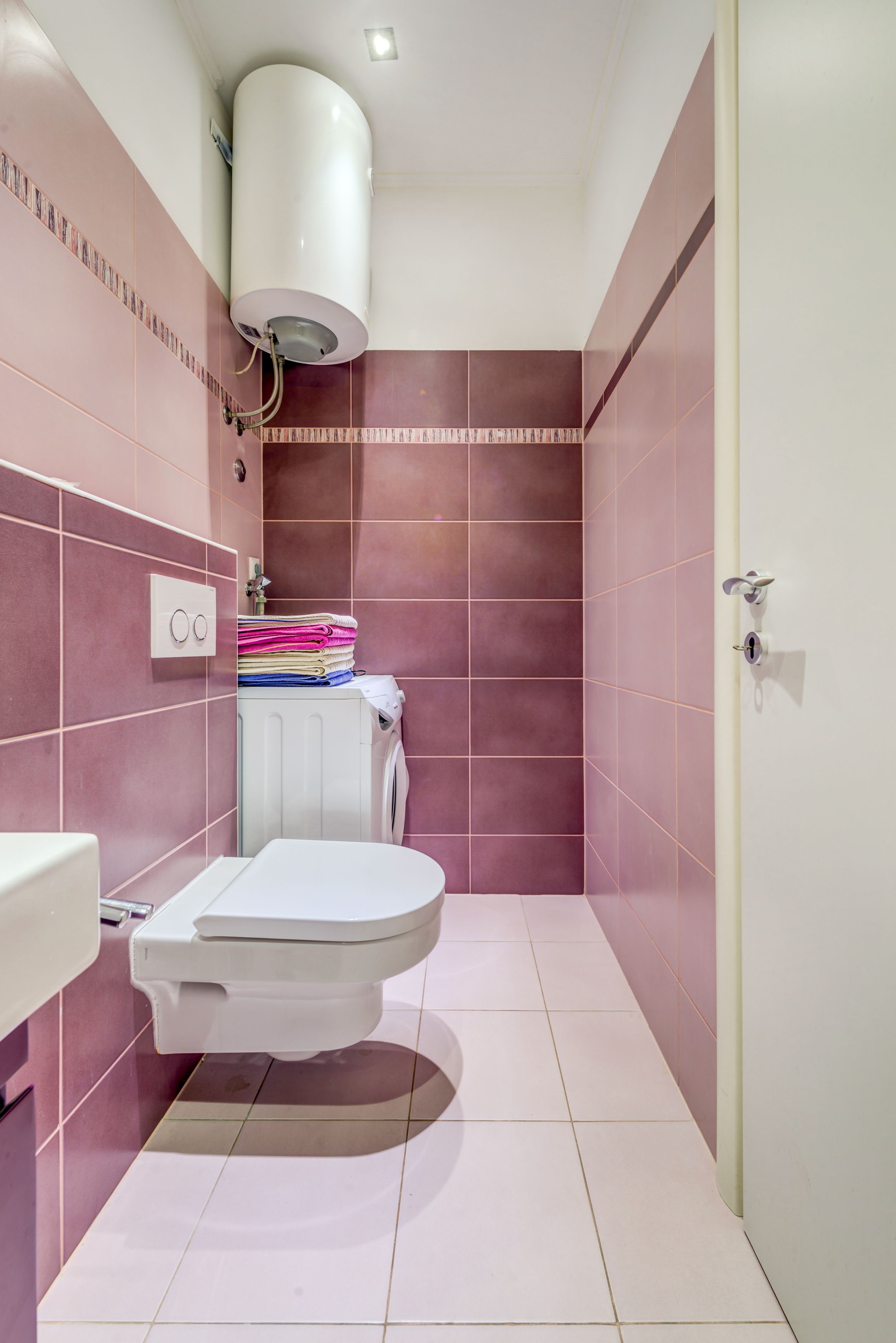 Une petite salle de bain comprenant des toilettes, un radiateur et une pile de serviettes pliées.