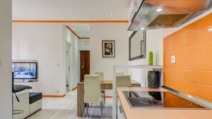 A modern kitchen with a built-in stove, a dining area with chairs, and a television in the corner. - Split Suites Centre Apartman Anka (Split)