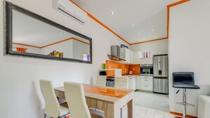 A modern kitchen with white cabinets, a stainless steel refrigerator, and a wooden dining table with two chairs. - Split Suites Centre Apartman Anka (Split)