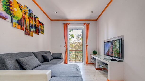 A modern living room with a grey sofa, a white armchair, a flat-screen TV, and a large window with curtains. - Split Suites Centre Apartman Anka (Split)