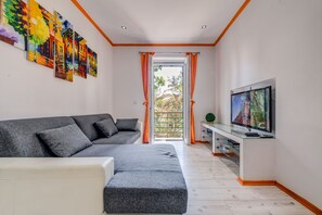 Relax in this stylish living room with a sofa, armchair, and large window offering a view of lush greenery.