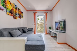 Relax in this stylish living room with a sofa, armchair, and large window offering a view of lush greenery.