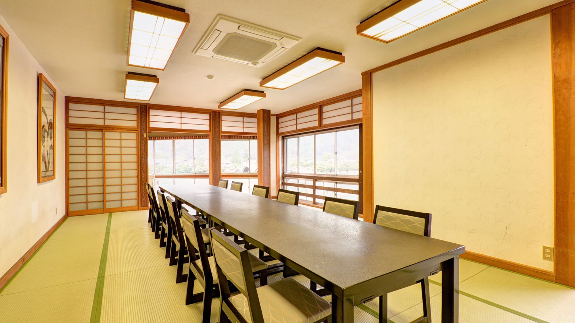 A traditional Japanese meeting room with tatami mats, a long table, and sliding doors.