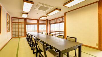 A traditional Japanese meeting room with tatami mats, a long table, and sliding doors.
