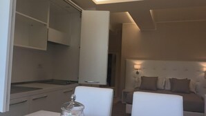 A modern hotel room with a dining area, a bed with a headboard, and a nightstand.