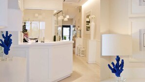 A modern hotel lobby with a central reception desk, framed artwork on the walls, and decorative blue coral sculptures.
