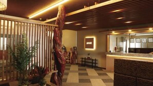 A reception area with a wooden reception desk, a large wooden sculpture, and a checkered floor. - Iki Sakana Senmon Ryokan Atarashiya (Wakayama)