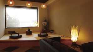 Une pièce avec des tatamis servant de sièges, une grande fenêtre et un vase japonais traditionnel.