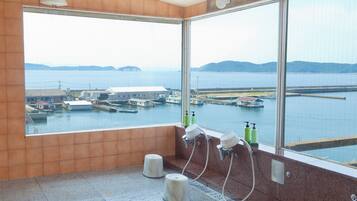 A bathroom with large windows, a tiled floor, and a view of a harbor with boats.