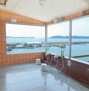 A bathroom with large windows, a tiled floor, and a view of a harbor with boats. - Iki Sakana Senmon Ryokan Atarashiya (Wakayama)