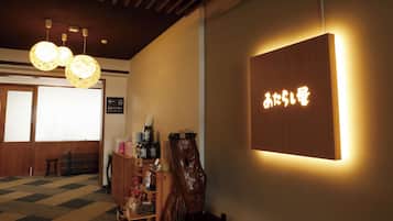 A reception area with a wooden reception desk, a wooden sculpture, and a wall-mounted sign with Japanese characters.