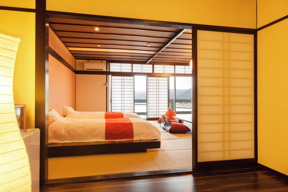 Una habitación con una cama y varios futones, algunos con cojines y mantas rojas.