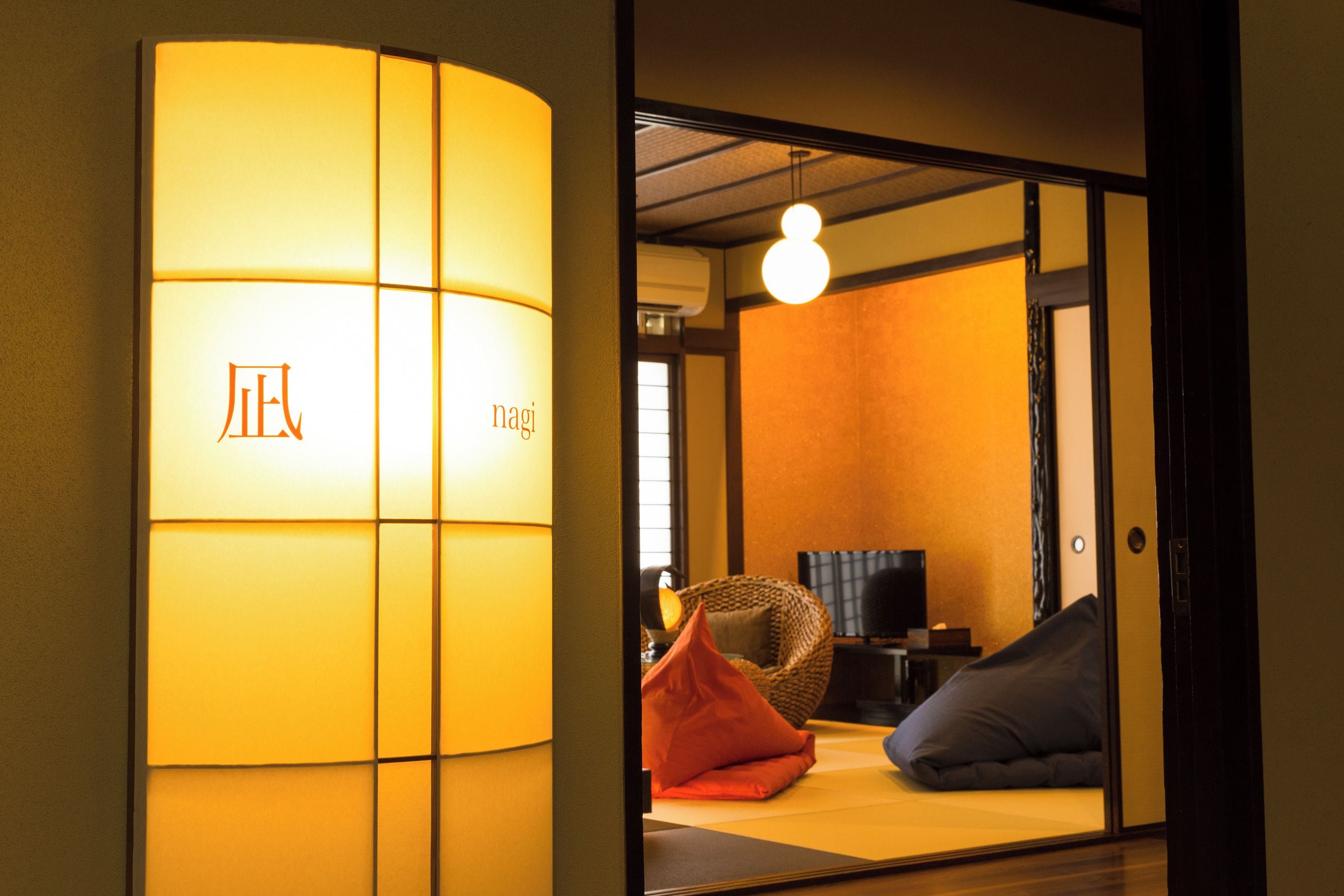 Un interior japonés tradicional con puertas correderas, una lámpara, un sofá y un televisor.