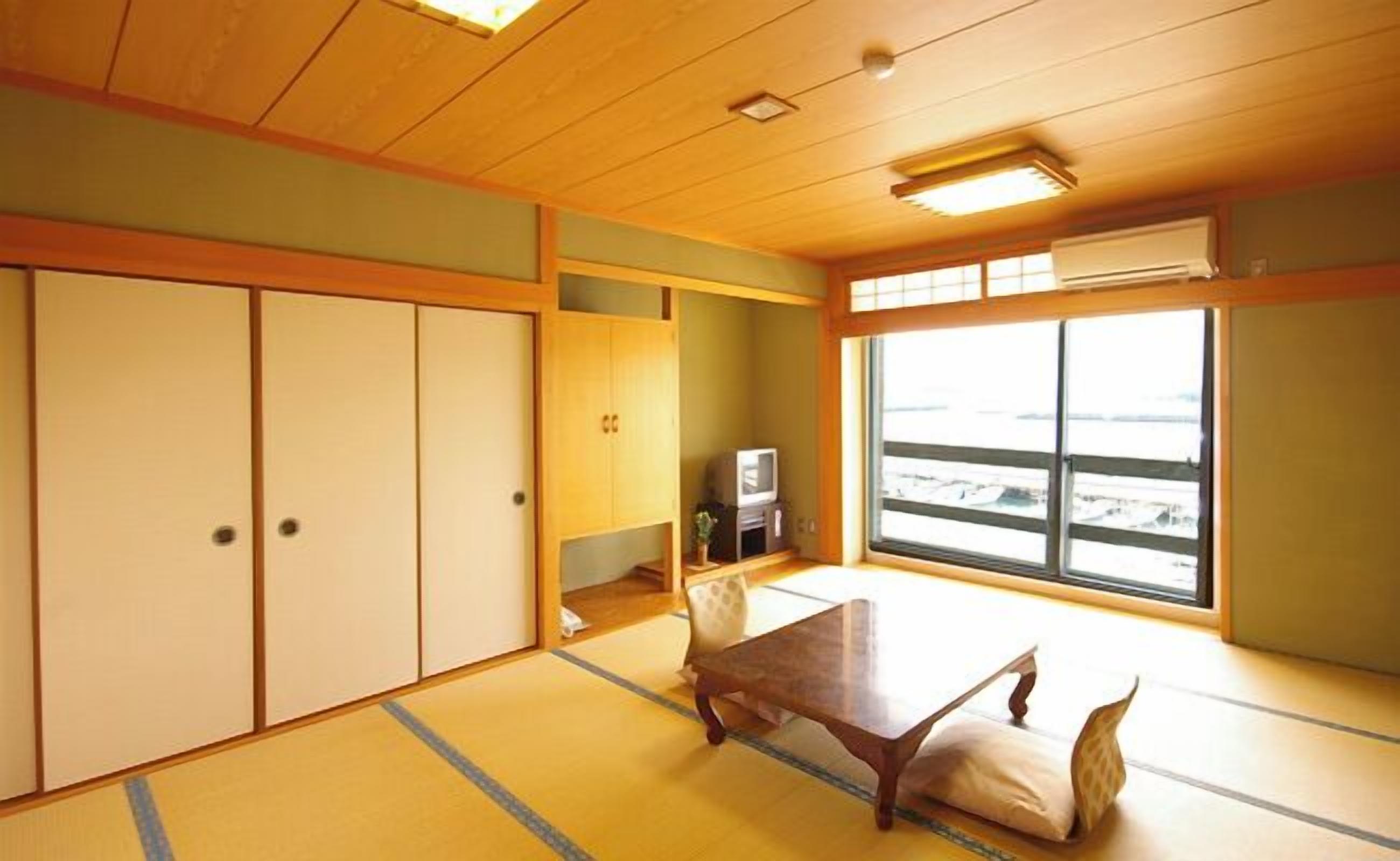 Una habitación japonesa tradicional con suelo de tatami, una mesa baja y puertas correderas.