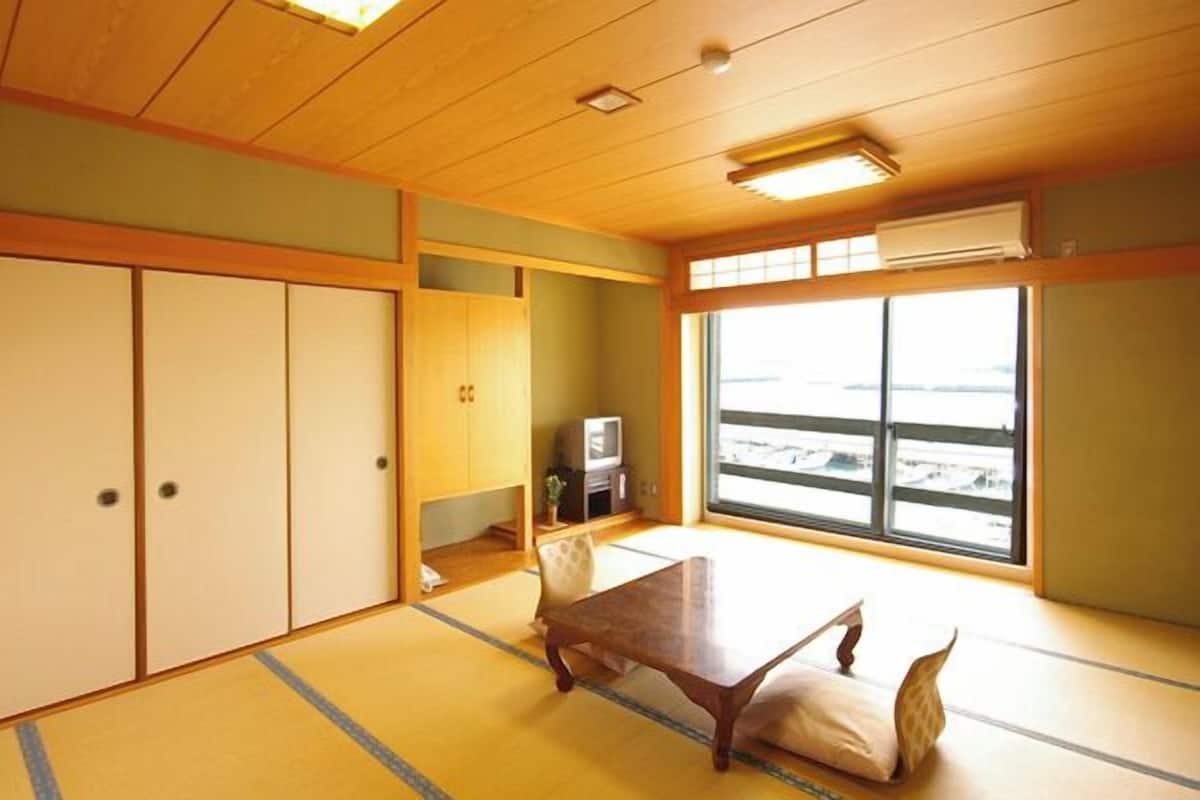 Una habitación japonesa tradicional con suelo de tatami, una mesa baja y puertas correderas.
