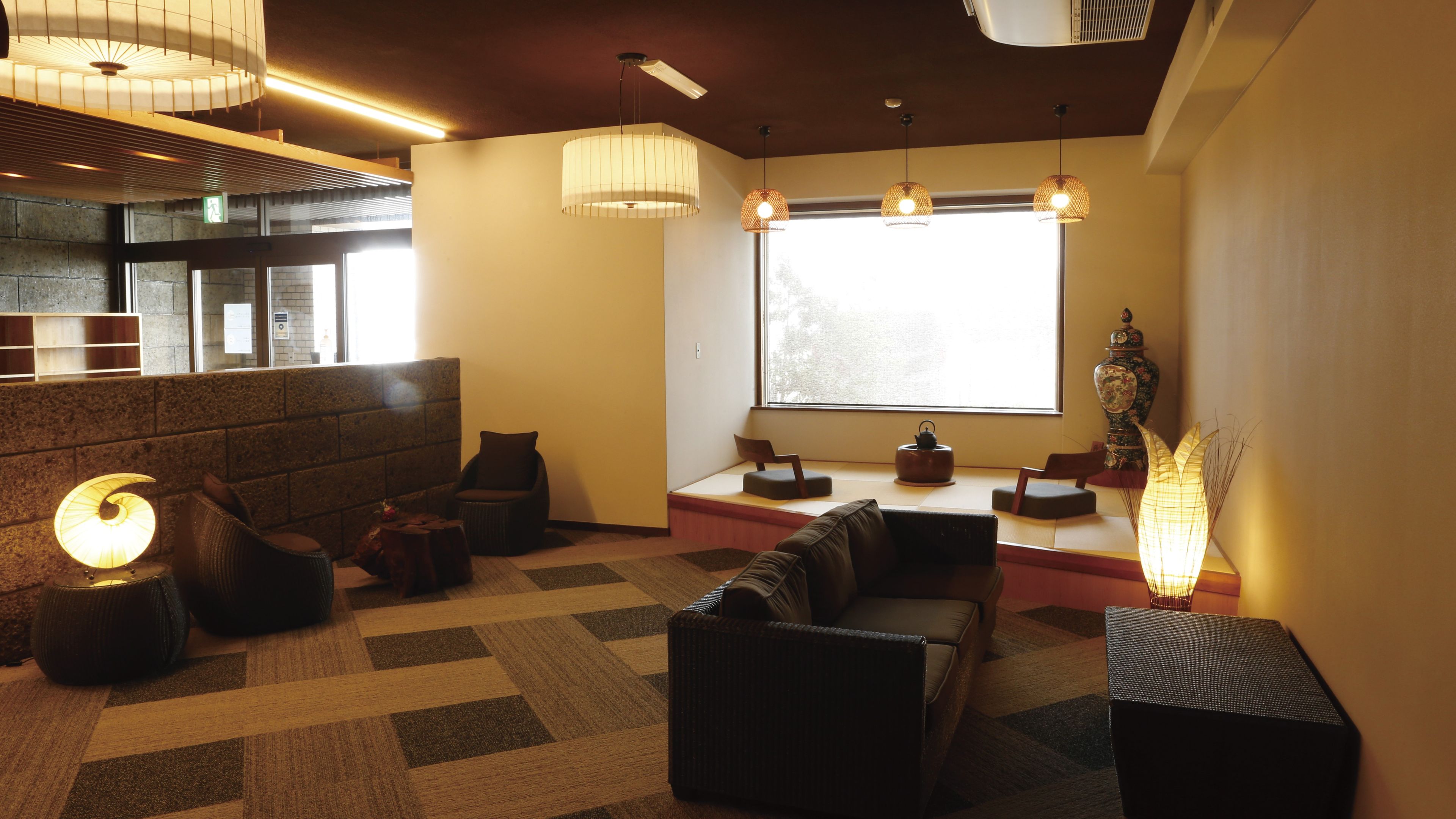 A modern interior with seating areas, a large window, and a decorative vase.