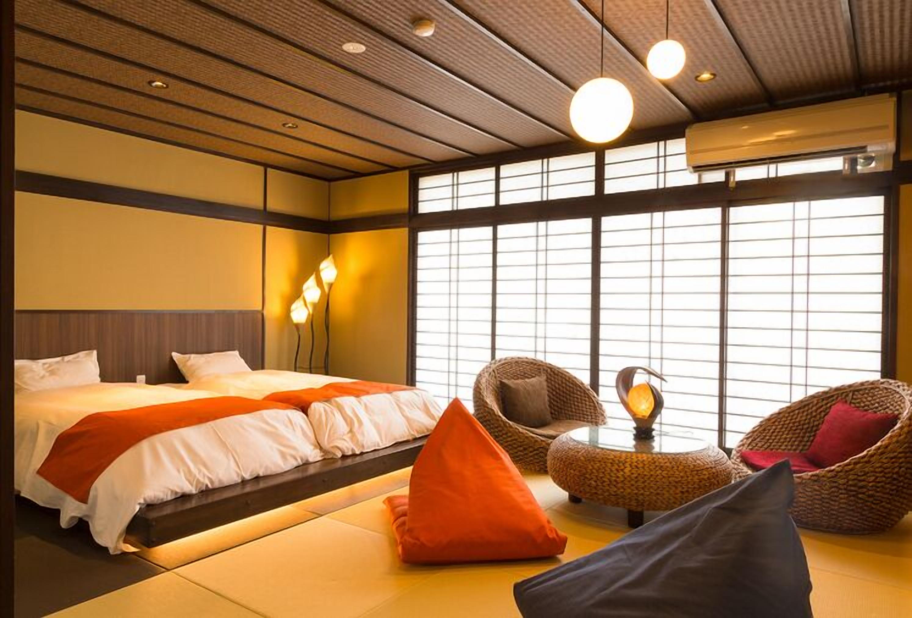 A hotel room with a bed, two chairs, a small table, and a large window.