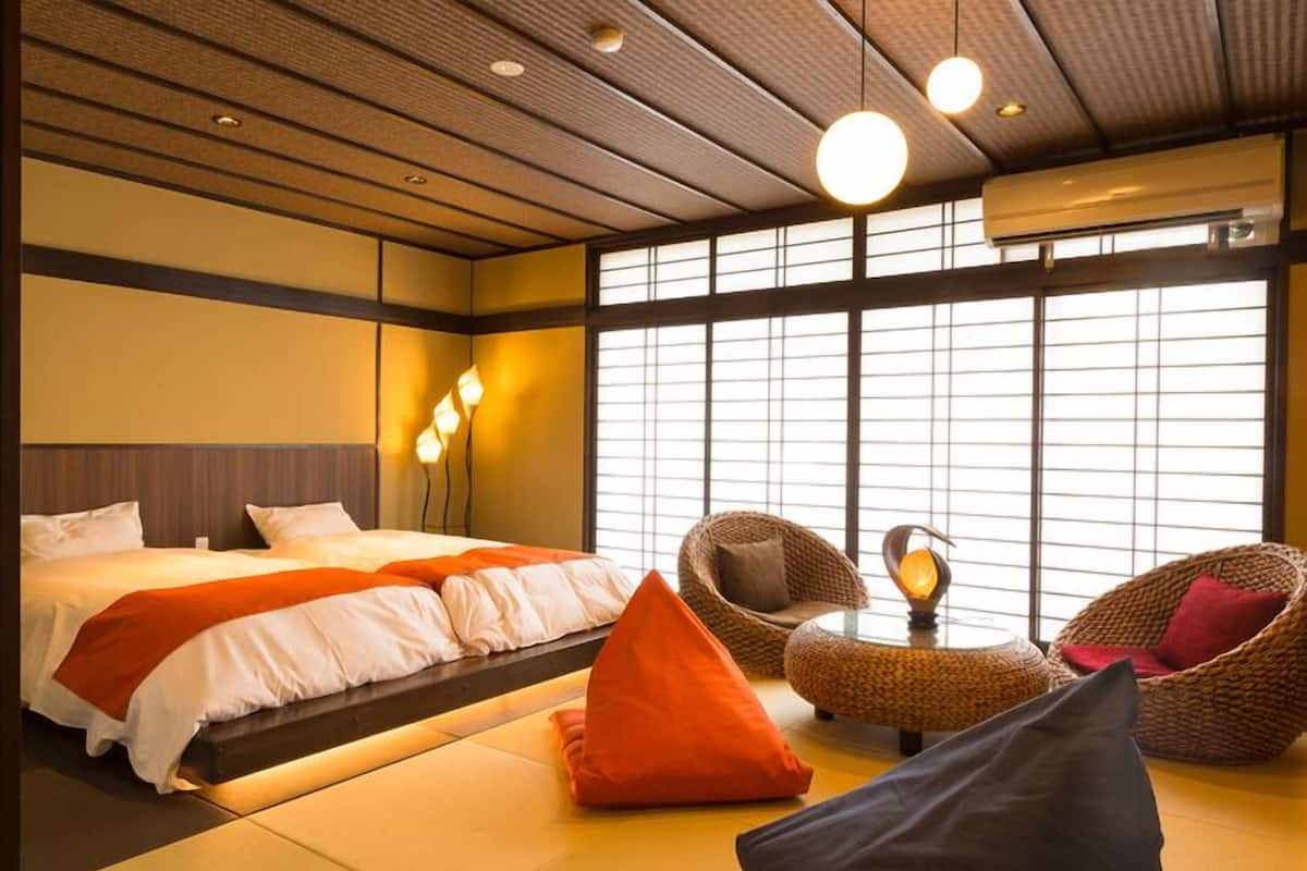 Habitación de hotel con cama, dos sillones, una mesita y un ventanal amplio.
