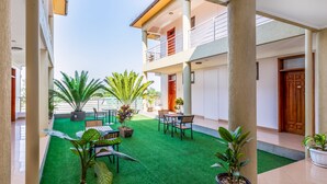 A courtyard with artificial green turf, potted plants, and outdoor furniture. - Entebbe Travelle'rs Inn (Entebbe)