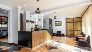 A hotel lobby with a reception desk, seating area, and a dining space. - Entebbe Travelle'rs Inn (Entebbe)