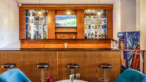 A bar area with wooden paneling, a television, shelves of liquor bottles, and bar stools. - Entebbe Travelle'rs Inn (Entebbe)