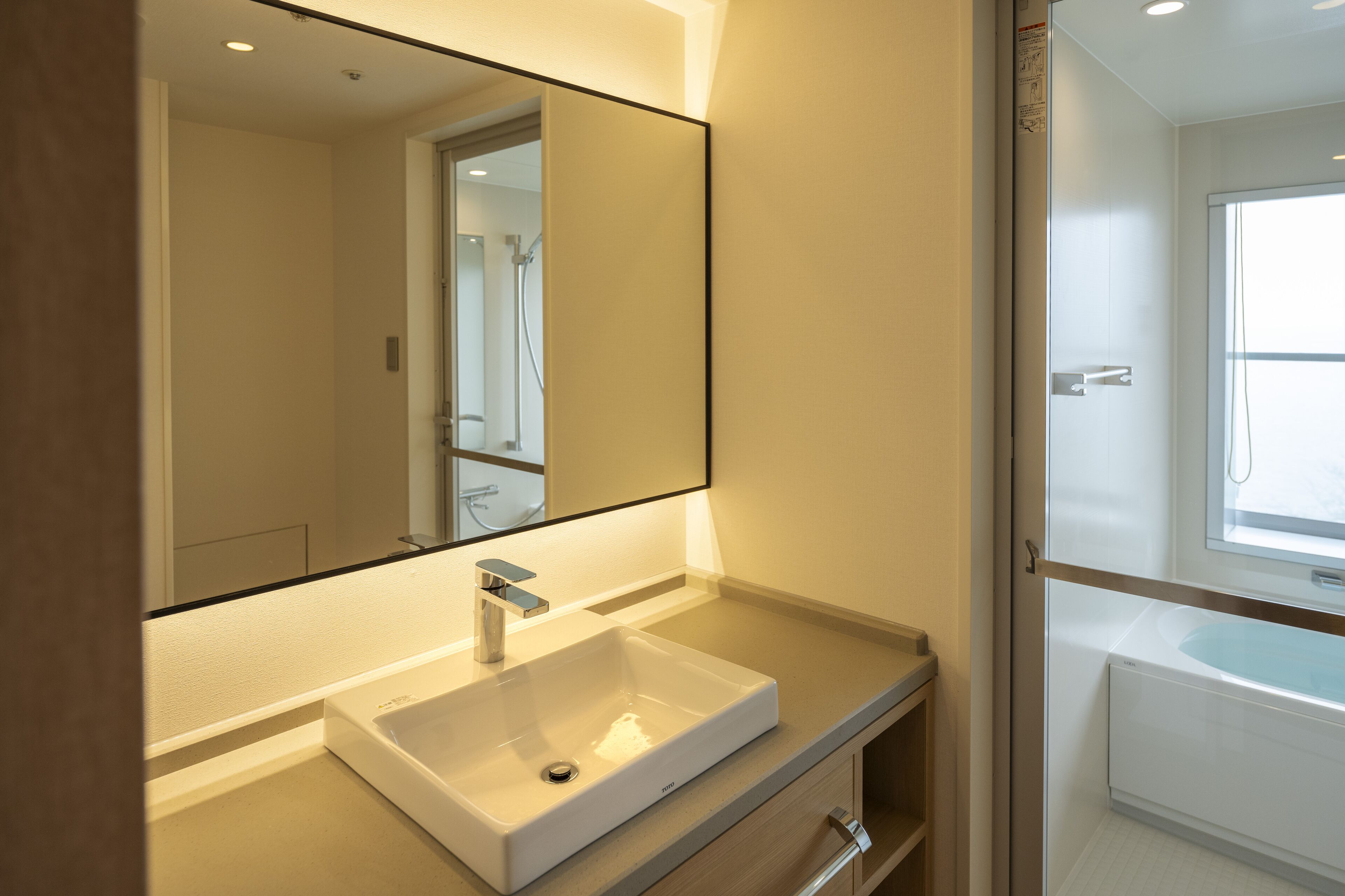 Une salle de bain moderne avec un grand miroir, un lavabo blanc et une baignoire.