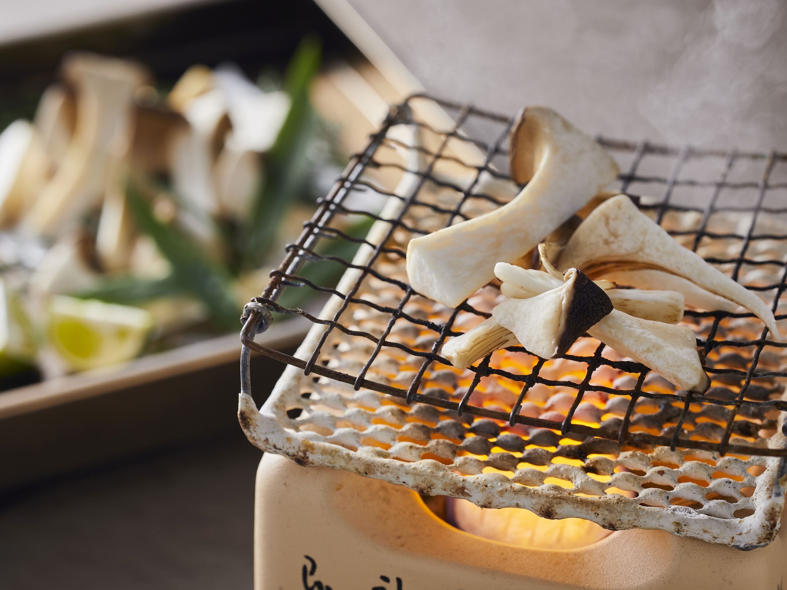 A grill with mushrooms and a white container with text.