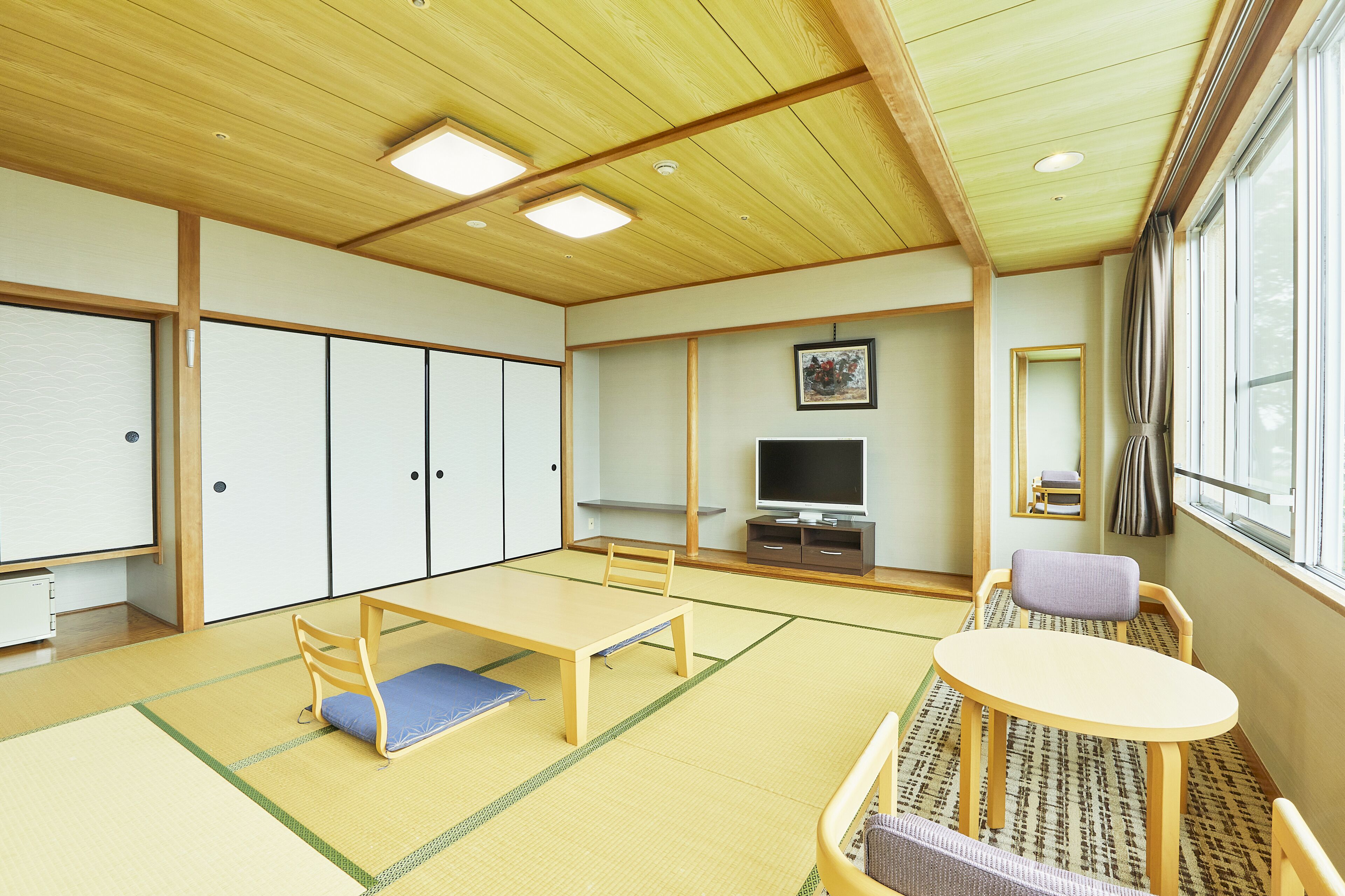 A traditional Japanese-style room with tatami flooring, a low table, and a television.