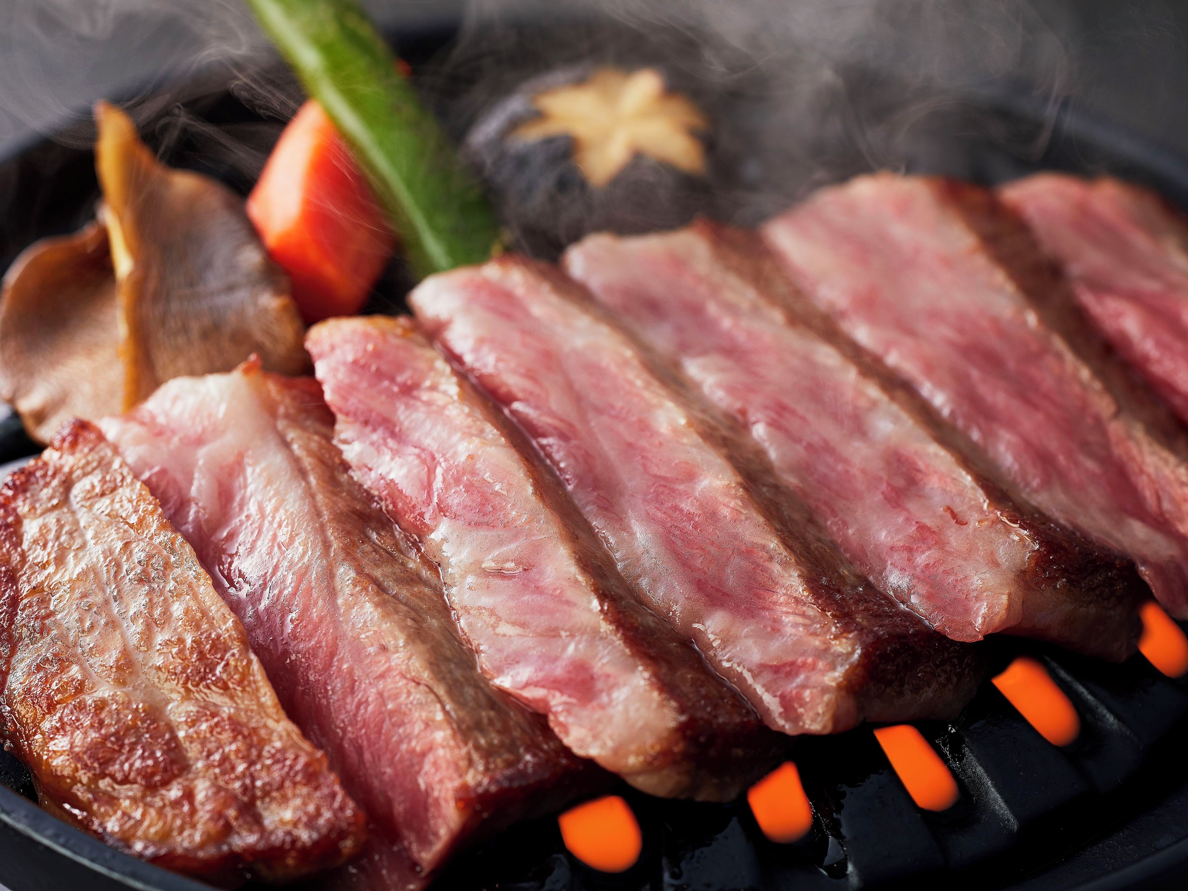 A close-up of grilled meat with visible grill marks, accompanied by vegetables and a star-shaped item, likely a decorative element.