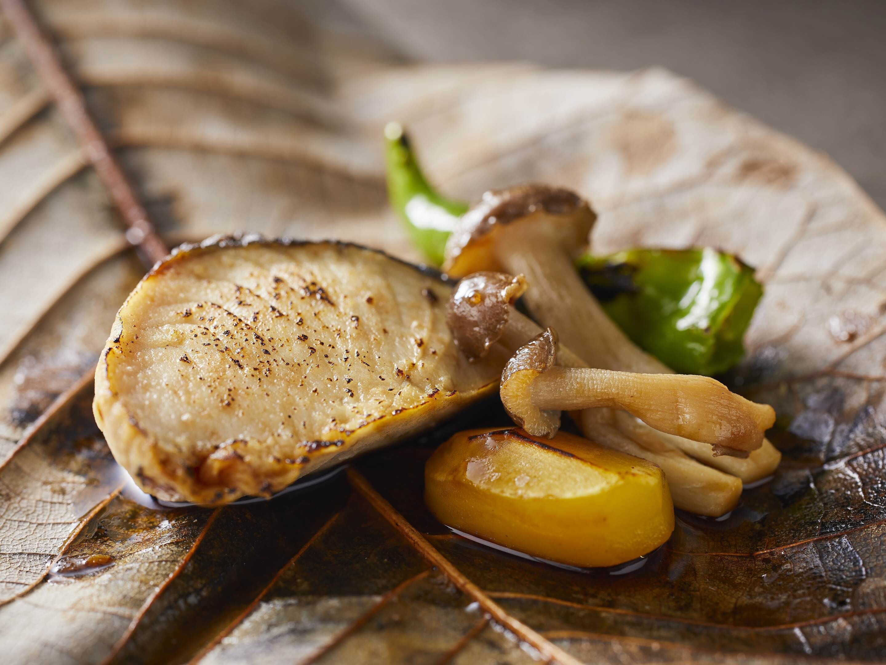 Un piatto di cibo con carne, funghi e una fetta di patata.