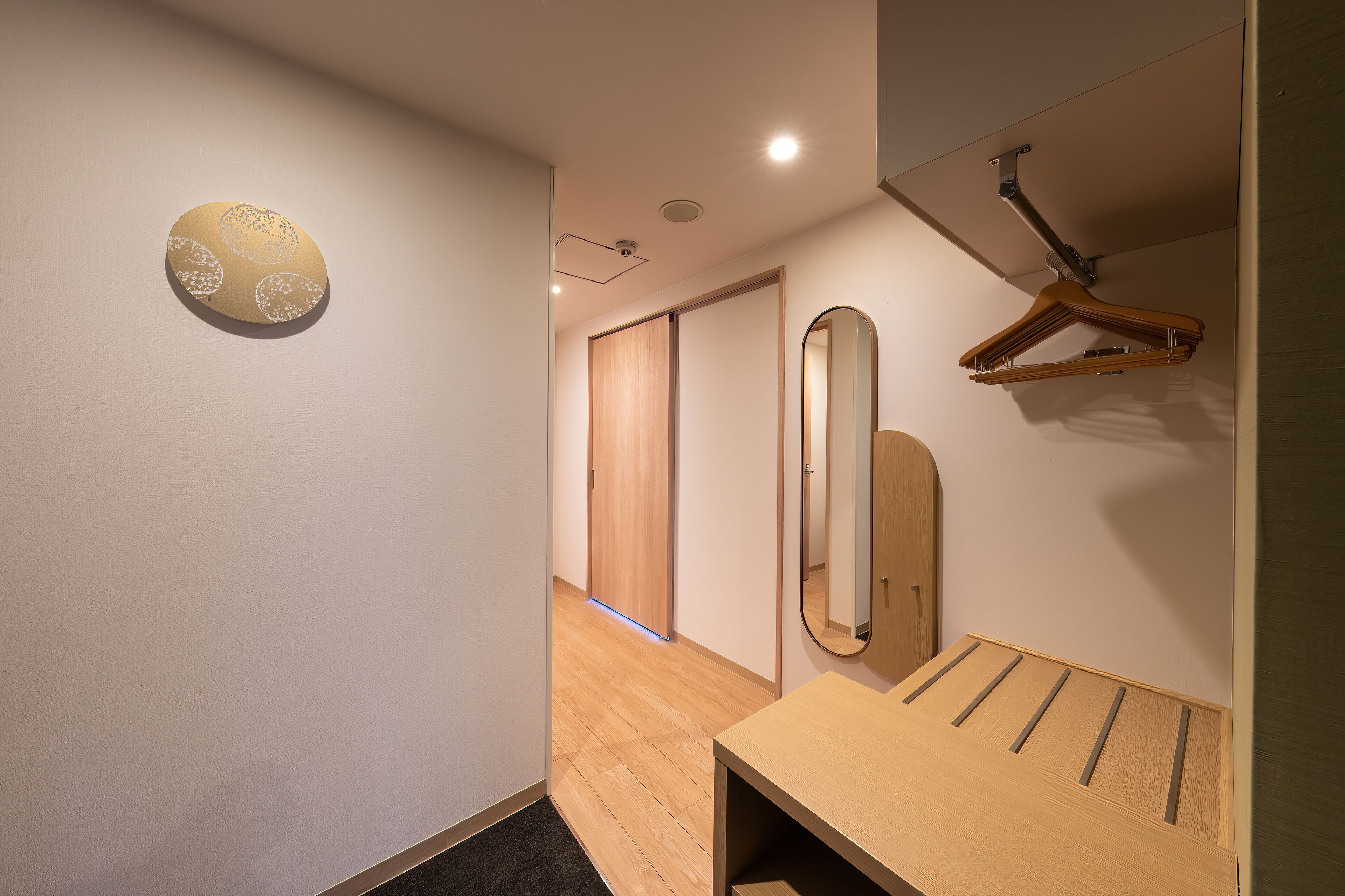 A hallway with a wooden floor, a wooden door, and a mirror on the wall.