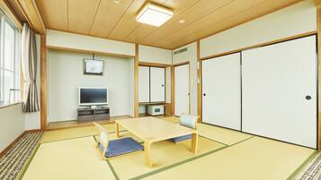 Une pièce de style japonais traditionnel, avec un sol recouvert de tatamis, une table basse, un téléviseur et des portes coulissantes.
