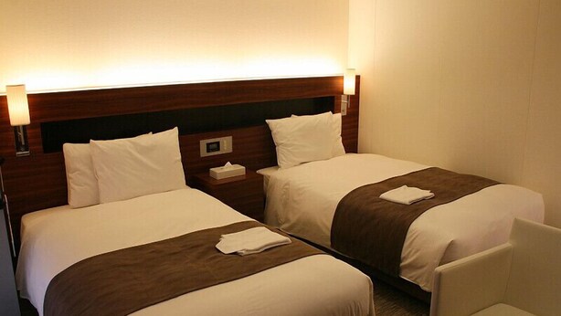 A hotel room with two beds, a nightstand, a chair, and a lamp. - Shizuoka Daiichi Hotel (Shizuoka)