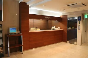 A reception desk with a 'FRONT' sign, a computer, and a telephone.