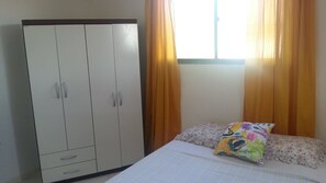 A bedroom with a bed, a wardrobe, and curtains.