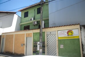 A building with a green facade, multiple air conditioning units, and a sign indicating it is a residential building.