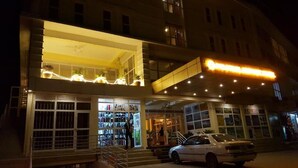 A hotel with a brightly lit entrance, a visible staircase, and a parked car in front. - Pulickal Airport Hotel (Entebbe)