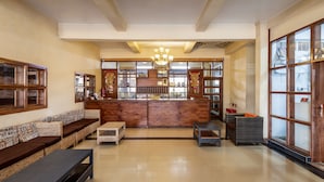 A spacious lobby with a reception desk, cushioned seating, and a chandelier. - Pulickal Airport Hotel (Entebbe)