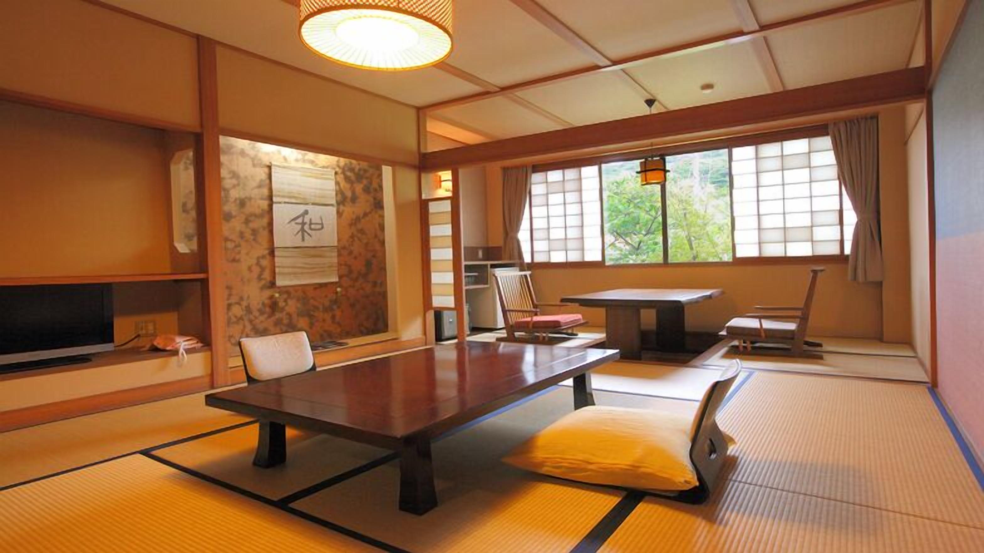 A traditional Japanese room with tatami flooring, a low table, chairs, and a television.