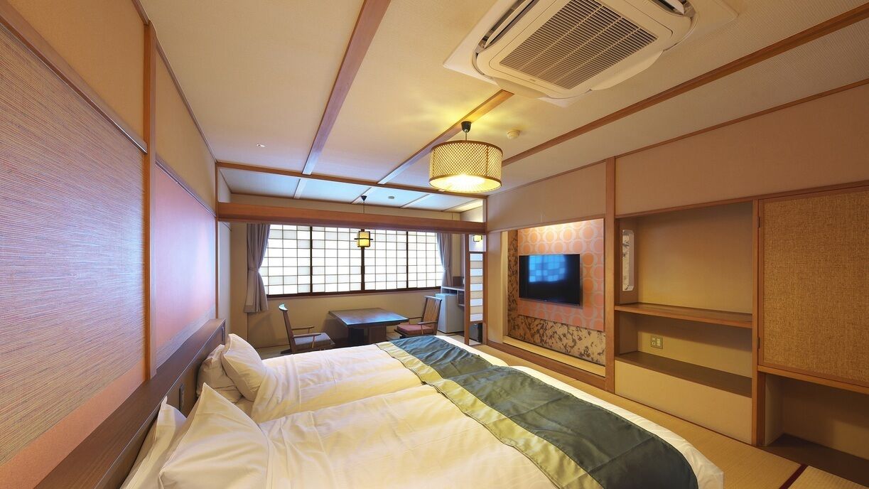 A hotel room with a bed, a TV, a desk, and a window.