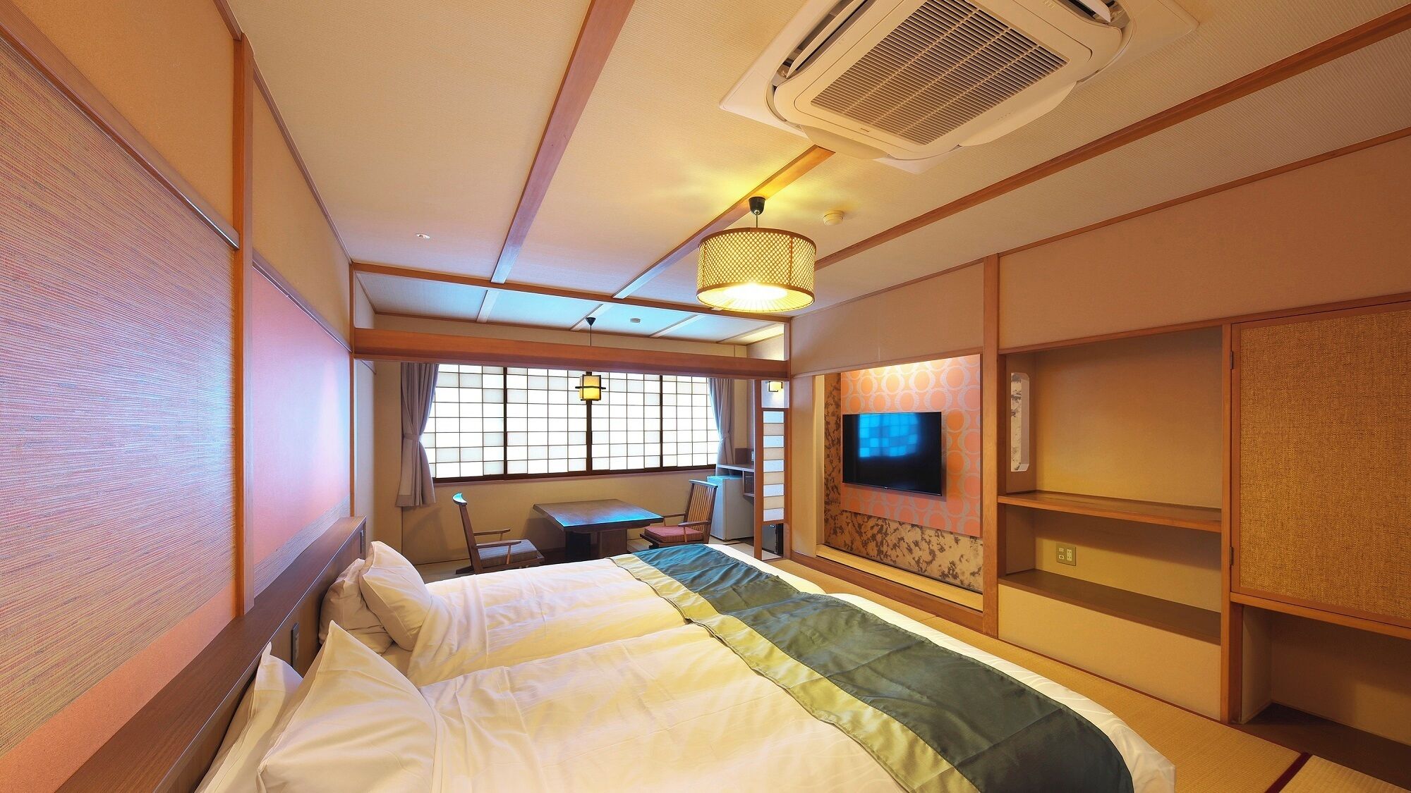 A hotel room with a bed, a desk, a TV, and a window with curtains.