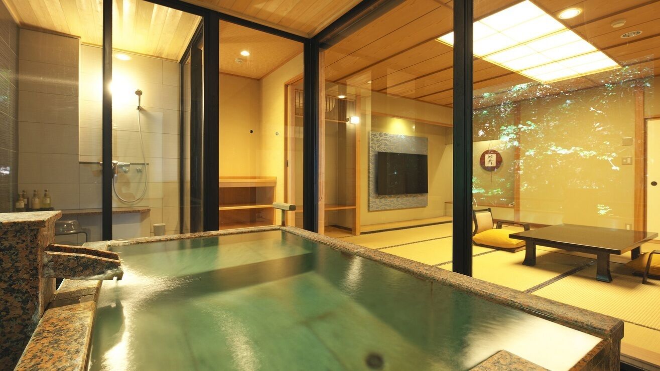 A modern interior with a large indoor pool, wooden flooring, and a seating area with tables and chairs.
