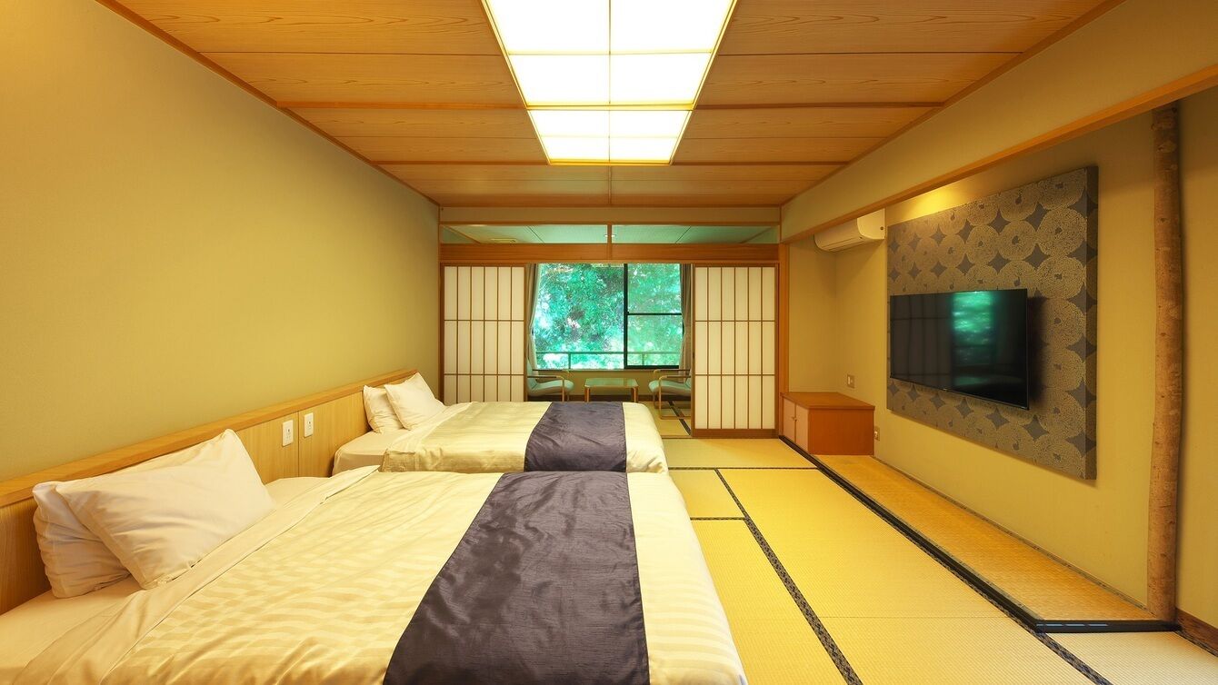A traditional Japanese room with tatami flooring, two beds with pillows, a television on the wall, and a window with a view of greenery.