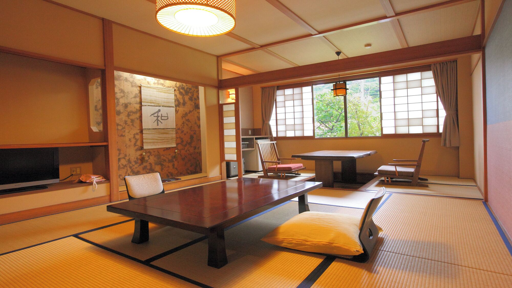 A traditional Japanese room with tatami flooring, a low table, a television, and sliding doors.