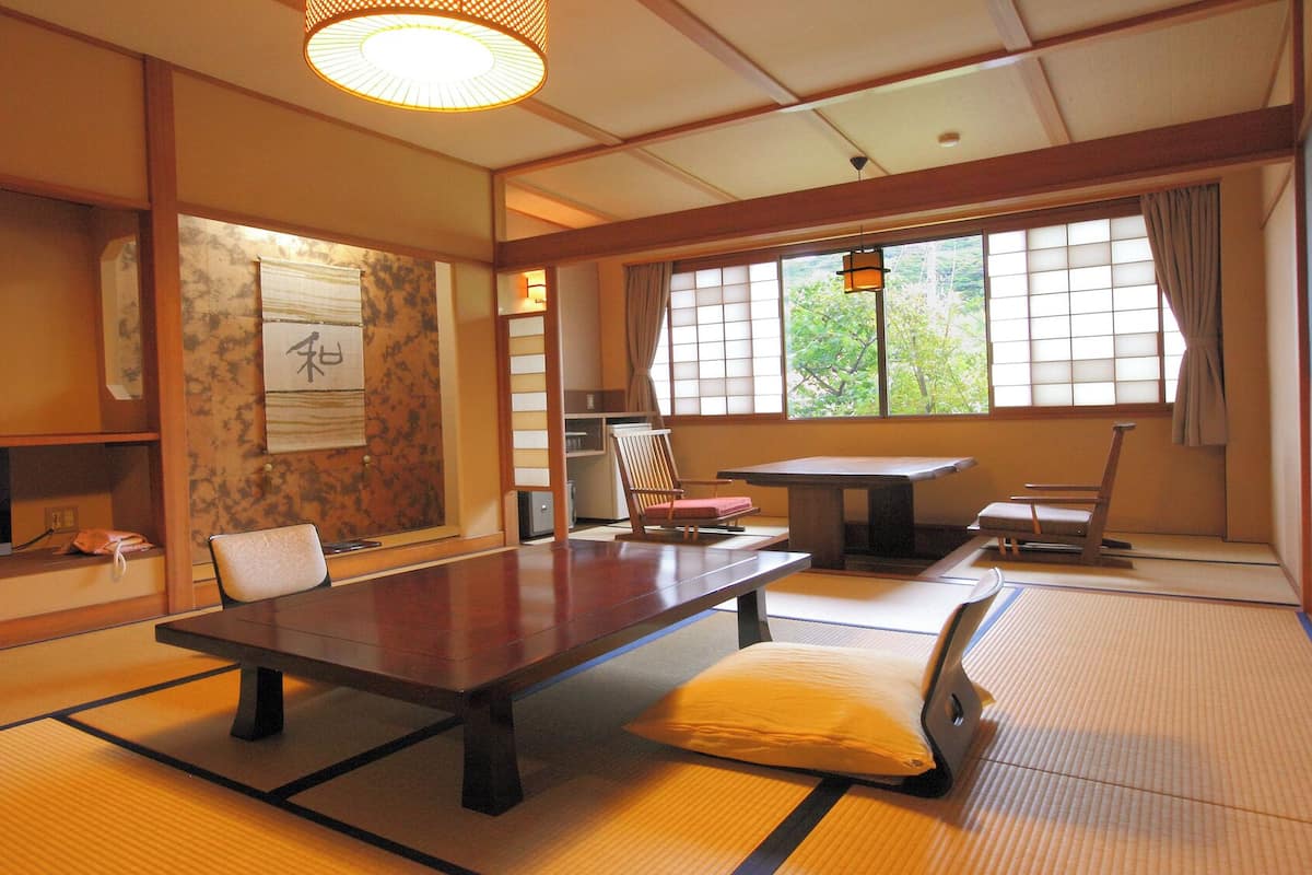 Una habitación japonesa tradicional con suelo de tatami, una mesa baja, un televisor y puertas correderas.